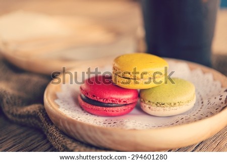 Macaroon dessert served with coffee on a table, brown wood.