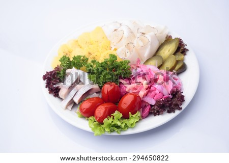Restaurant food of delicious diner platter of marinated cucumbers tomatoes sauerkraut with pieces of lard herring and boiled potatoes decorated with herbs isolated on white, horizontal picture
