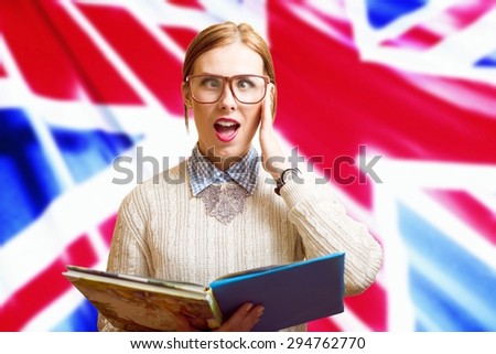 Portrait of funny young pretty female in glasses holding books with the UK flag on the background. Learn English