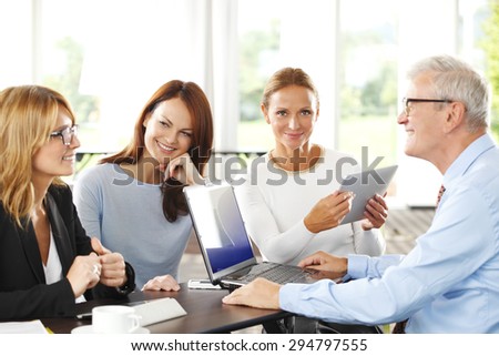 Portrait of senior businessman sitting in front of laptop and presenting his idea to businesswomen. Middle age businesswoman talking about financial plan. 