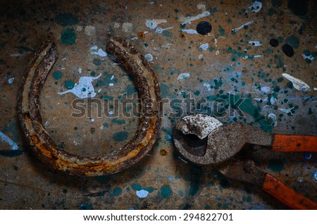 Rusty old horseshoe and pliers on a grungy background