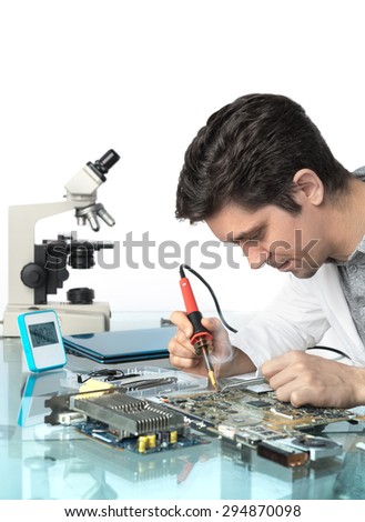 Young energetic male tech or engineer repairs electronic equipment, top of the picture isolated, space for your text, focus on the solrer tip and eyes