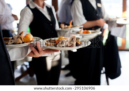 Waiters carrying plates with meat dish at a wedding Royalty-Free Stock Photo #295106906