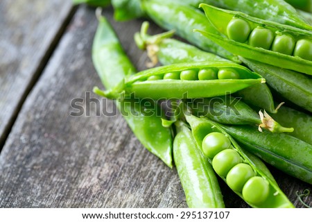 pea pods on wooden table Royalty-Free Stock Photo #295137107