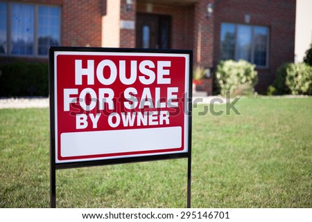 House For Sale By Owner Sign in a front yard of a house