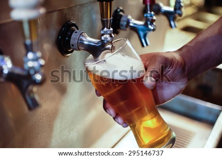 African American bartender filling beer glass from a bar tap