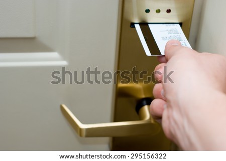 Photo of hand inserting a key card into an electronic hotel door security lock to unlock the door.
