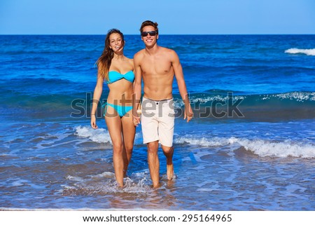 Beautiful young couple walking in the beach shore on summer vacation