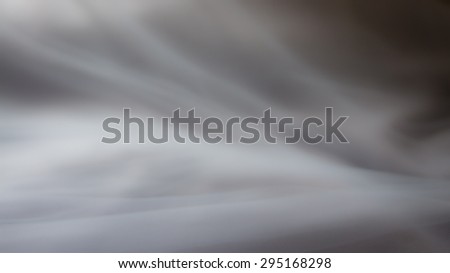 Gray background abstract cloth or fabric.Liquid waves illustration of wavy folds of silk texture satin. Wallpaper design of elegant curves material. Defocused.