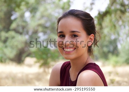 Attractive young teenage girl posing for senior portraits in a park