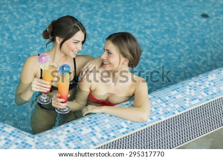 Young women in the pool with cocktails
