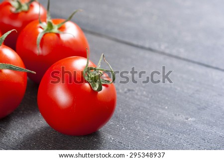 red tomatoes on old black wooden table 