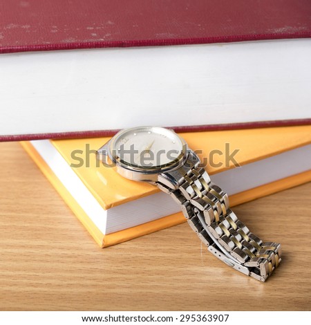 book with watch on wood background