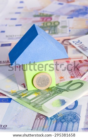 Real estate - investment concept with a toy house on Euro banknotes. Image with shallow depth of field.
