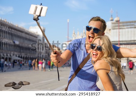 Funny tourist couple making selfie with selfie stick Royalty-Free Stock Photo #295418927