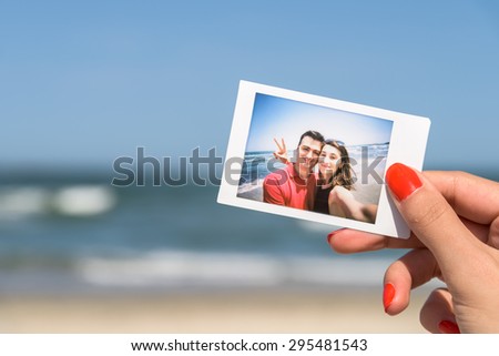 Girl Hand Holding Instant Photo Of Young Happy Couple, focus on hand