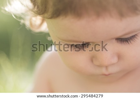 Closeup of small cute joyful child boy with blonde curly hair sunny day outdoor on natural background, horizontal picture