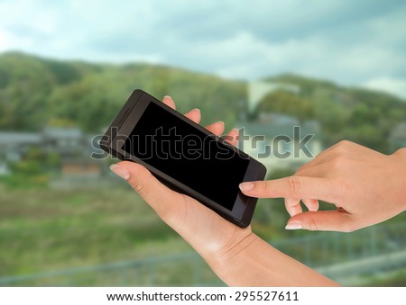 Closeup of hands using a smart phone, nature background.