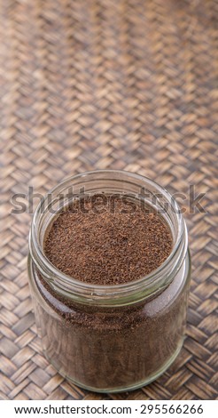 Dried processed tea leaves in a mason jar over rustic wicker background 