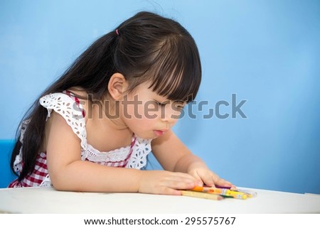 Cute Asian girl sitting happily drawing, coloring.