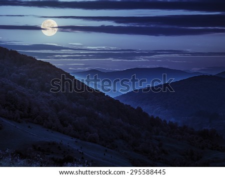 autumn landscape. fog from forest surrounds the mountain top at night in full moon light