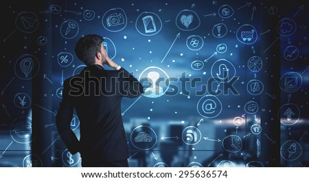Businessman drawing social media connection scheme on glass window with night cityscape background
