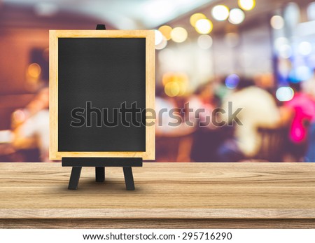 Blackboard menu with easel on wooden table with blur restaurant background, Copy space for adding your content