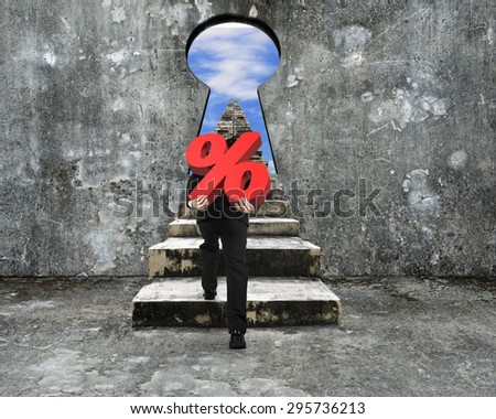 Man carrying percentage sign climbing old concrete stairs toward keyhole, with view of sky clouds.