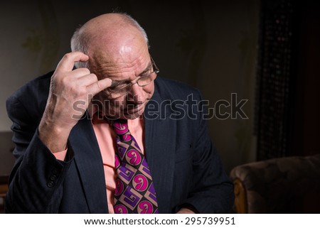 Close up Contemplative Old Businessman in Formal Suit, Scratching his Bald Head While Looking Down.
