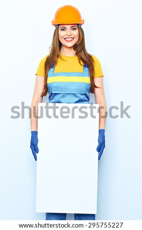 Woman hold white blank business board dressed in builder uniform. Smiling female model.  blue coveralls, glow.