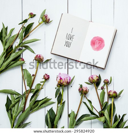 Peonies flowers with sketch book with hand-drown heart and print LOVE YOU. Hipster interior room decoration.