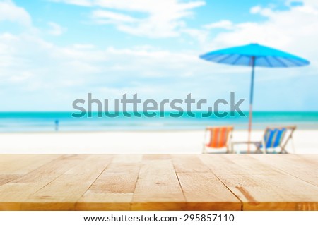 Wood table top on blur beach background with beach chairs and parasol - can be used for display or montage your products