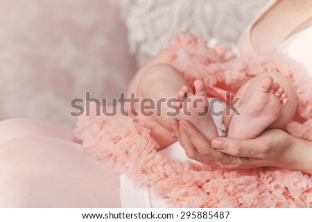 Happy young family, a mother holding foot her firstborn. The concept of happiness of motherhood.