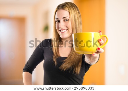 Pretty girl holding a cup of coffee on unfocused background