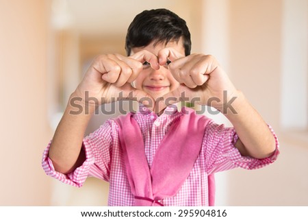 Boy making a heart with his hands inside house