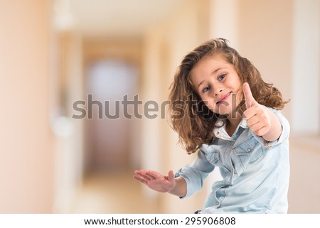 Blonde little girl with thumb up inside house