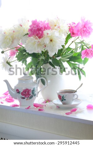 Still-life with tea and a bouquet of peonies on a white window sill
