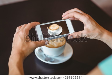 Woman taking picture with her smartphone at the cafe