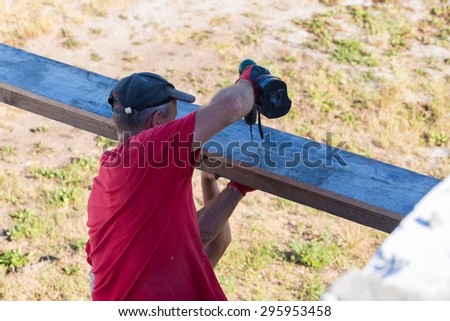 Photo of worker working on home construction in summertime. Polish manual worker.