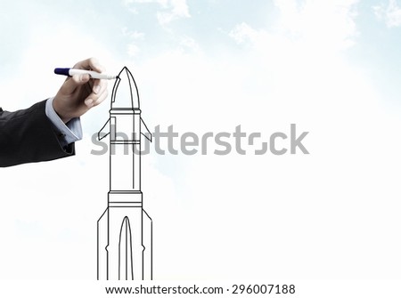 Close up of male hand drawing rocket with marker