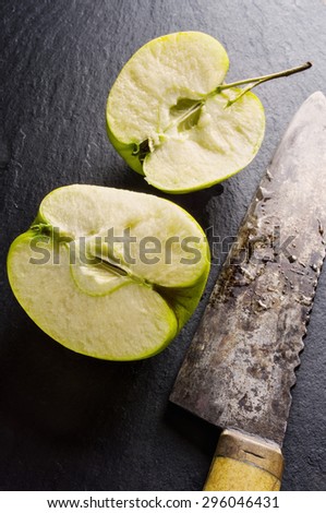 Kitchen knife and green apple, on stone cutting board