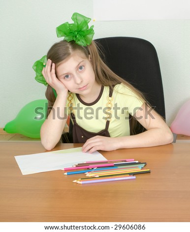 The girl sitting at a table with color pencils