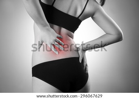 Woman with backache. Pain in the  human body. Black and white photo with red dot