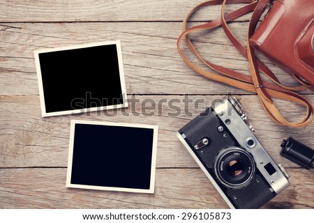 Vintage film camera and two blank photo frames on wooden table. Top view