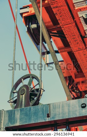 Business and commerce. Cranes at port area, lifting block, cargo container yard. Industrial detail, part of heavy machinery