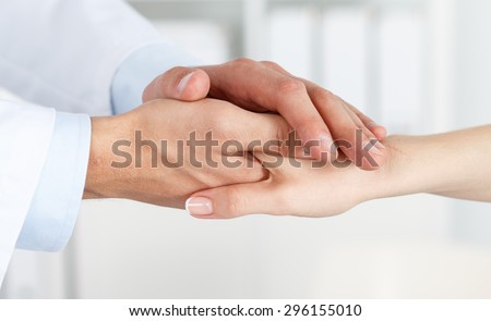 Friendly male doctor's hands holding female patient's hand for encouragement and empathy. Partnership, trust and medical ethics concept. Bad news lessening and support. Patient cheering and support Royalty-Free Stock Photo #296155010