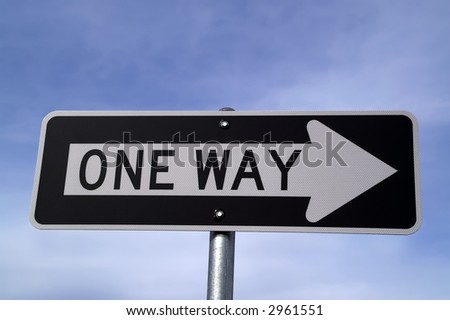 Black and white one way sign against blue sky