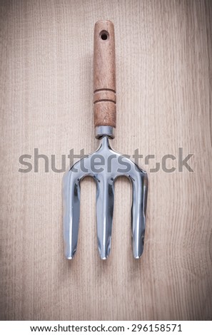 Stainless gardening trowel fork on wooden board agriculture concept.