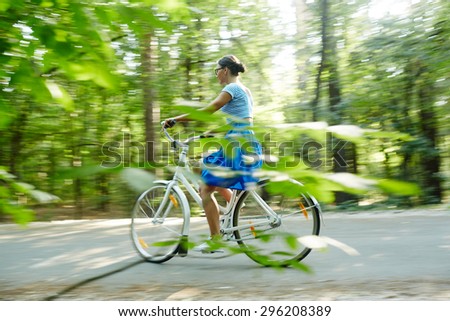 Modern girl riding bicycle in natural environment