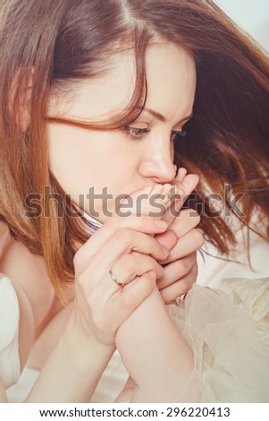 Young mother kissing feet of her child. Close-up portrait. The concept of happiness in the birth of children.
